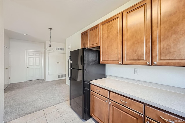 kitchen with light carpet, hanging light fixtures, and black refrigerator