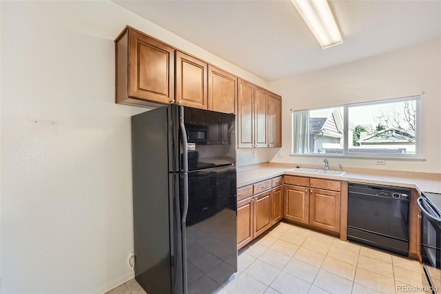 kitchen featuring black appliances, light tile patterned floors, and sink