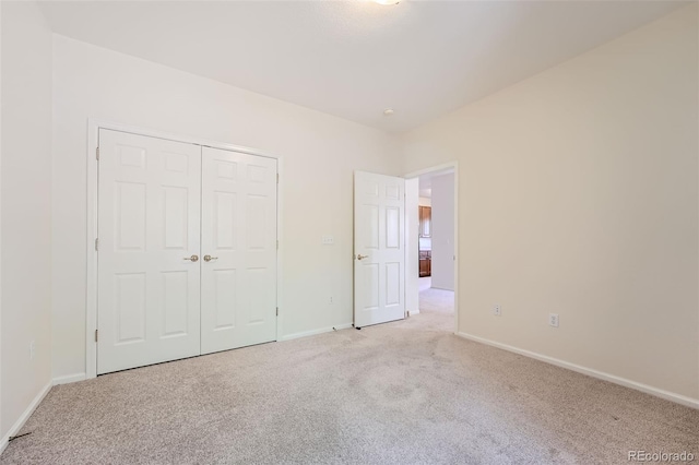 unfurnished bedroom featuring light carpet and a closet