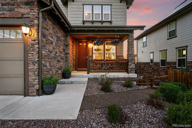 7949 S Elk Way, Aurora, CO 80016 - exterior entry at dusk featuring a porch and stone siding