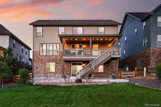 7949 S Elk Way, Aurora, CO 80016 - back of property at dusk featuring an outdoor fire pit, a patio area, stairway, and stone siding