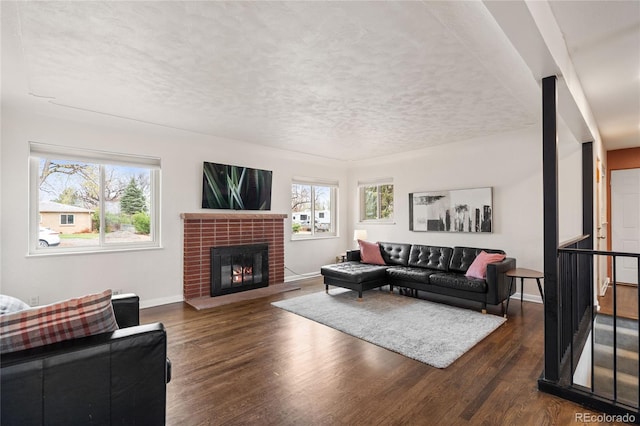 living room with baseboards, wood finished floors, a fireplace, and a textured ceiling