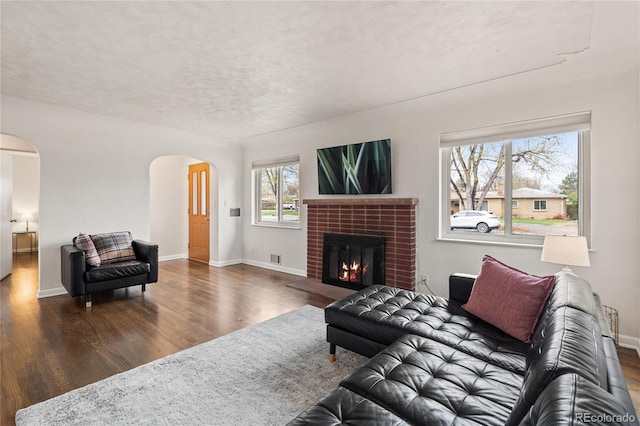 living area featuring arched walkways, a textured ceiling, wood finished floors, and a wealth of natural light