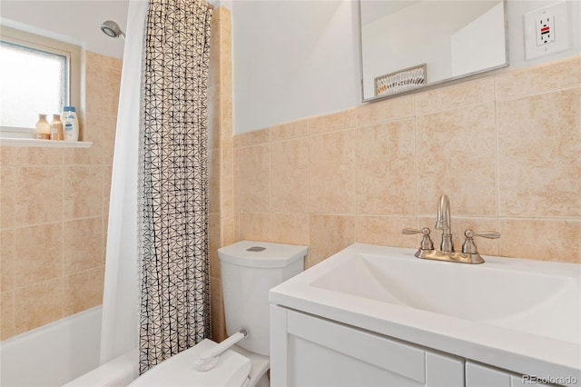 bathroom featuring toilet, vanity, shower / bath combo with shower curtain, and tile walls