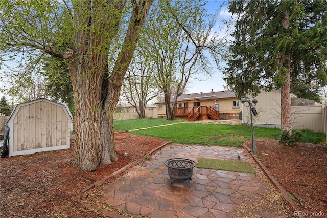 view of yard featuring a patio area, a storage shed, an outdoor fire pit, fence, and a wooden deck