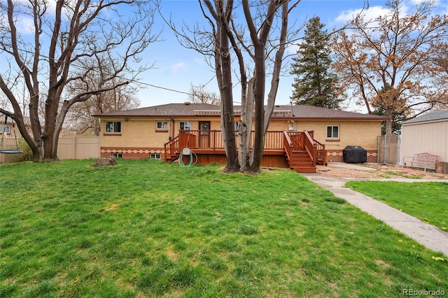 rear view of house featuring a lawn, brick siding, fence, and a deck