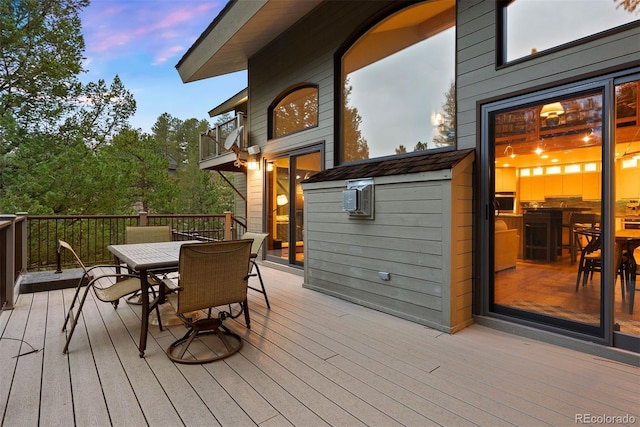 deck at dusk featuring outdoor dining area