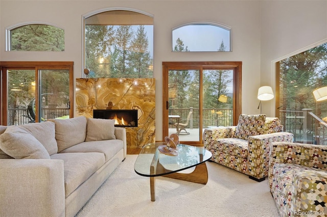 carpeted living area featuring a fireplace and a towering ceiling