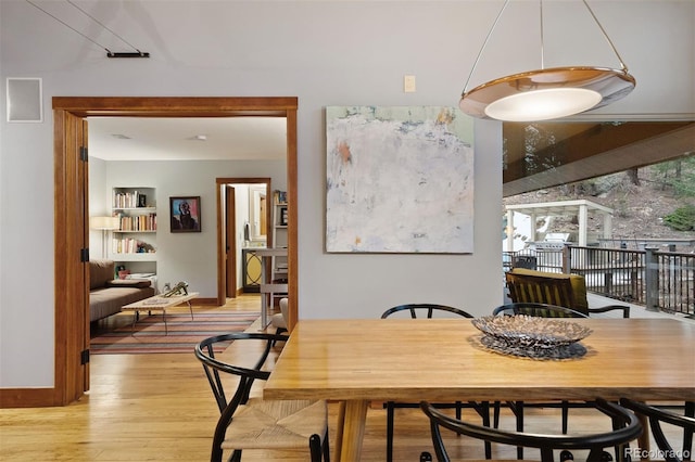 dining area featuring built in features, light wood-style flooring, and baseboards