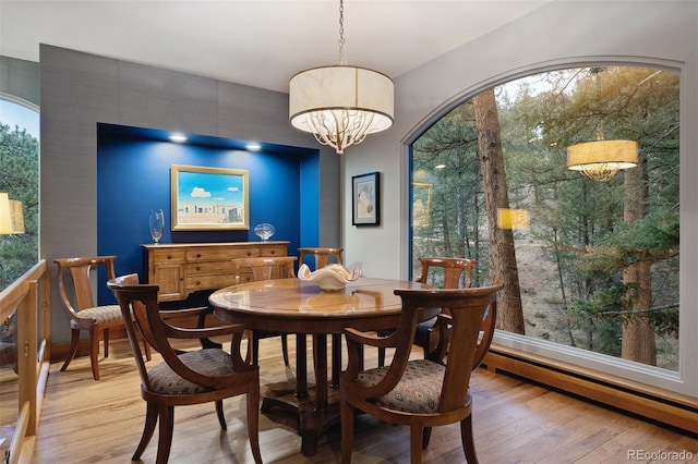 dining space with a chandelier, a healthy amount of sunlight, a baseboard radiator, and light wood-style floors