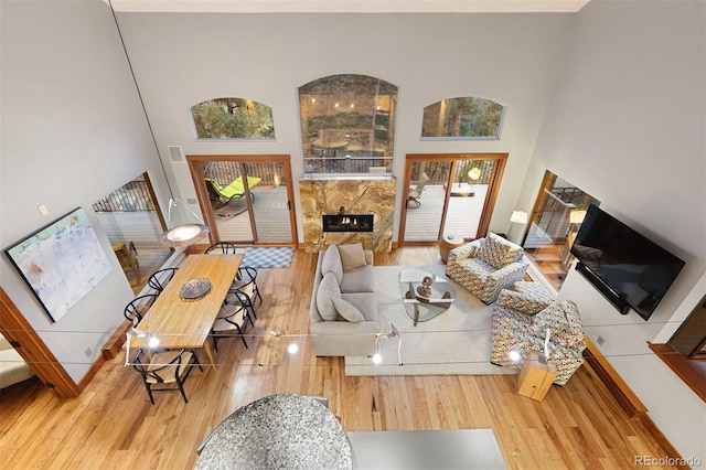 living area featuring a glass covered fireplace, a high ceiling, and wood finished floors