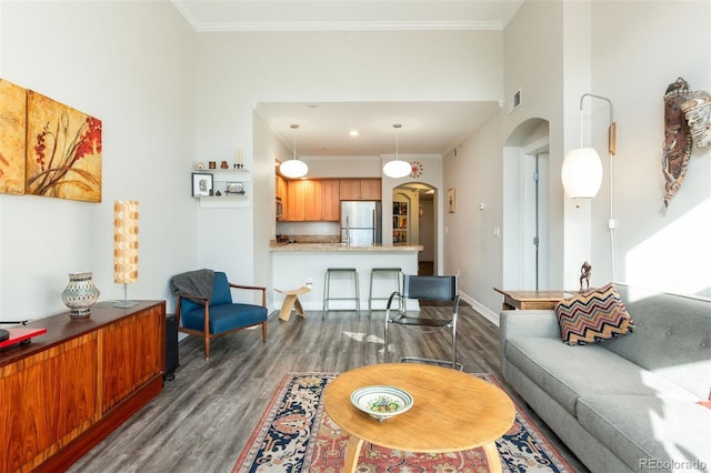 living room featuring ornamental molding, dark wood-type flooring, and a high ceiling