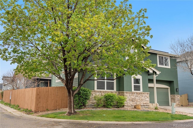 view of front of property featuring stone siding, stucco siding, fence, a garage, and driveway