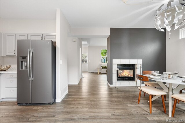 dining space with wood finished floors, a tile fireplace, and baseboards