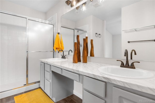 full bathroom with a stall shower, double vanity, and wood finished floors
