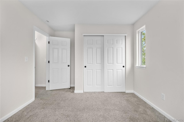 unfurnished bedroom with carpet flooring, baseboards, and a closet