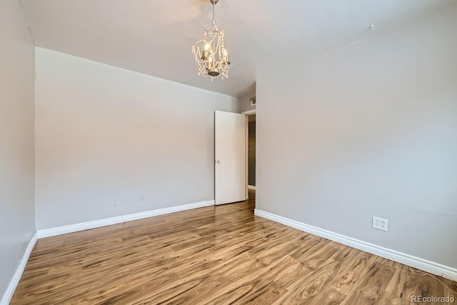 spare room featuring light hardwood / wood-style flooring and an inviting chandelier