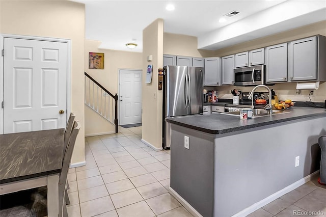 2143 Coronado Pkwy Unit C, Denver, CO 80229 - kitchen with stainless steel appliances, dark countertops, light tile patterned flooring, gray cabinetry, and a peninsula