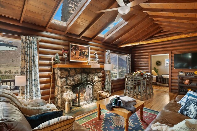 9850 Mohawk Trl, Cascade, CO 80809 - living room featuring wood finished floors, wooden ceiling, a skylight, a stone fireplace, and ceiling fan