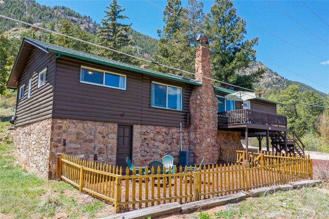 9850 Mohawk Trl, Cascade, CO 80809 - back of property featuring faux log siding, stone siding, a deck, stairway, and central AC unit