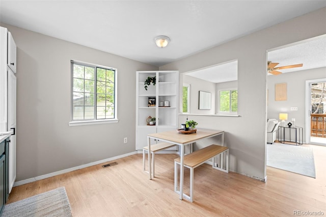 dining room featuring visible vents, light wood finished floors, and baseboards