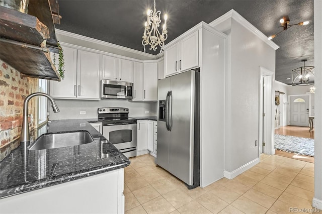 1024 34th St, Denver, CO 80205 - kitchen with appliances with stainless steel finishes, a chandelier, light tile patterned floors, dark stone countertops, and crown molding