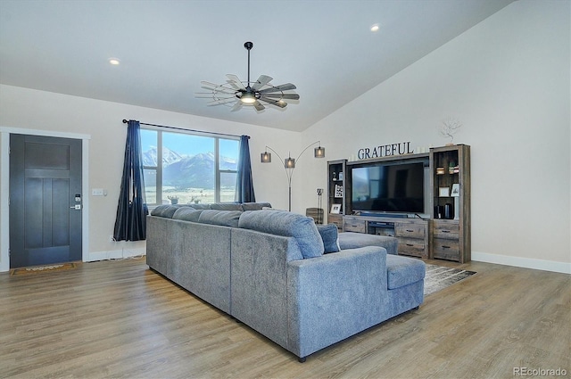 living room featuring ceiling fan, lofted ceiling, and light hardwood / wood-style flooring