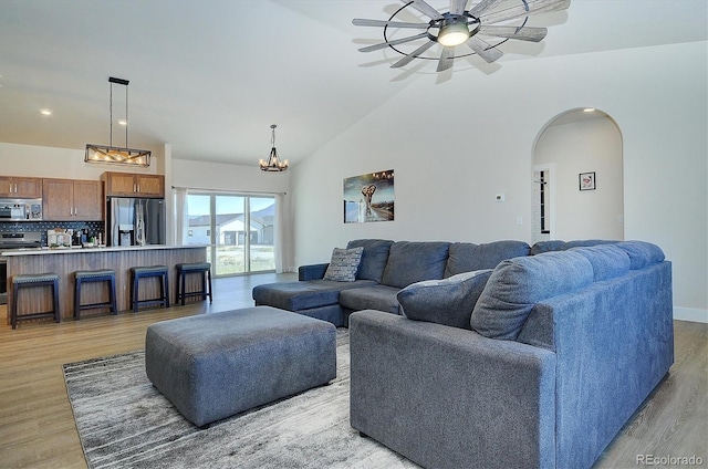living room with ceiling fan, high vaulted ceiling, and light hardwood / wood-style flooring