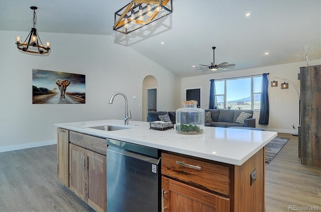 kitchen with sink, decorative light fixtures, vaulted ceiling, dishwasher, and an island with sink
