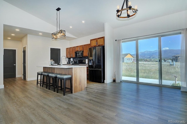 kitchen with pendant lighting, a kitchen breakfast bar, stainless steel fridge with ice dispenser, a mountain view, and a center island with sink