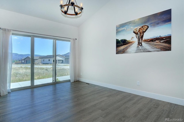 empty room featuring dark hardwood / wood-style flooring, a notable chandelier, and vaulted ceiling