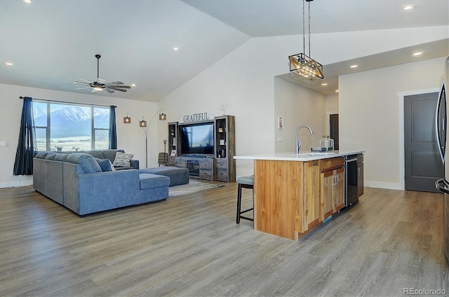 kitchen with an island with sink, ceiling fan, light hardwood / wood-style floors, and decorative light fixtures