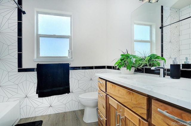 bathroom featuring vanity, wood-type flooring, tile walls, and toilet