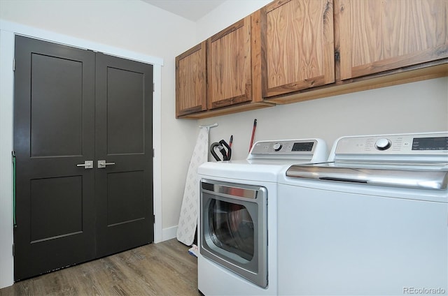washroom with cabinets, hardwood / wood-style flooring, and washer and dryer