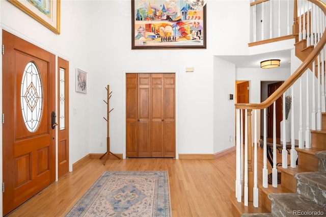 entryway featuring stairway, a high ceiling, and light wood finished floors