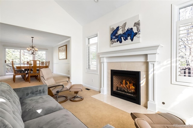 living room featuring an inviting chandelier, vaulted ceiling, baseboards, a tiled fireplace, and carpet flooring