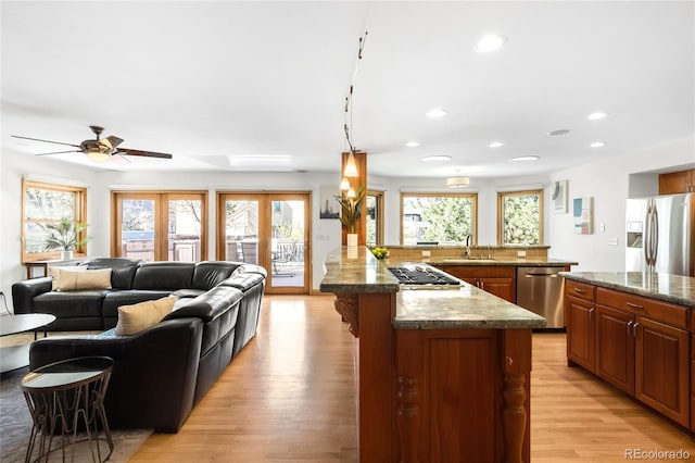 kitchen with light wood finished floors, a kitchen breakfast bar, stainless steel appliances, a sink, and ceiling fan