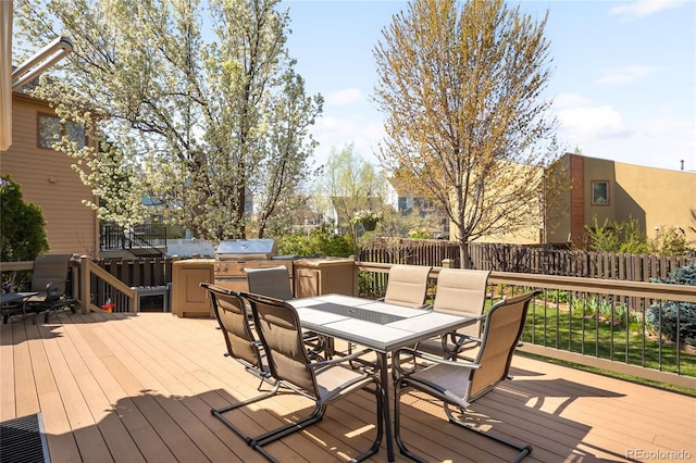 wooden terrace featuring outdoor dining space, an outdoor kitchen, a grill, and fence