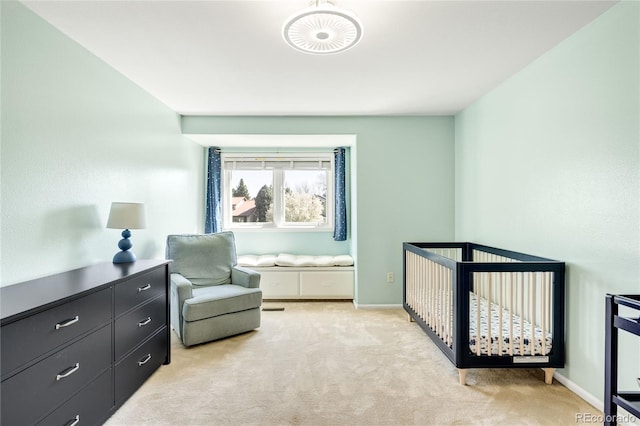 bedroom featuring light carpet, baseboards, and a crib