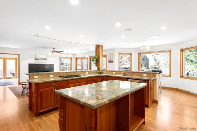 1437 Cassin Ct, Boulder, CO 80303 - kitchen with a spacious island, light wood-style floors, brown cabinets, open floor plan, and light stone counters