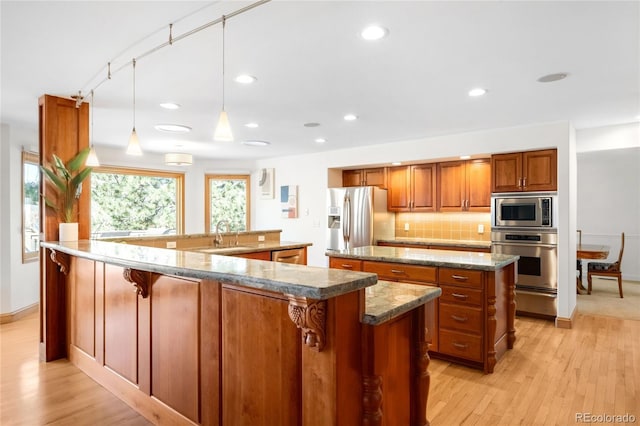 1437 Cassin Ct, Boulder, CO 80303 - kitchen with stainless steel appliances, a large island, brown cabinetry, light wood-type flooring, and a sink
