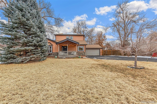 view of front property with a front lawn, a garage, solar panels, and a porch