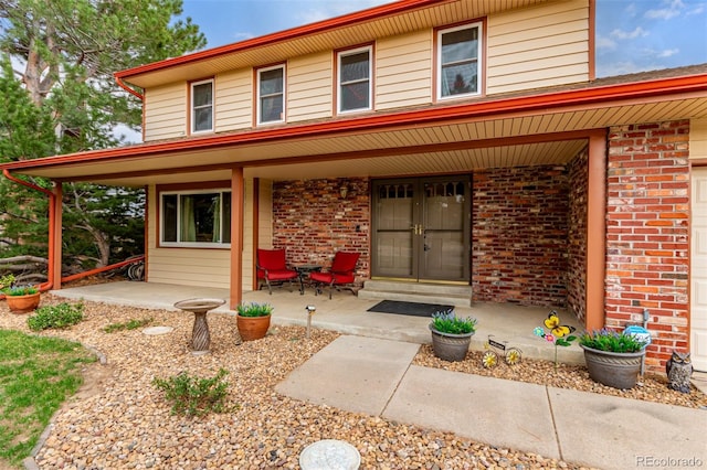 view of exterior entry with a porch and brick siding