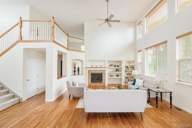 1477 Serene Dr, Erie, CO 80516 - living room with a ceiling fan, a high ceiling, wood finished floors, stairs, and a glass covered fireplace