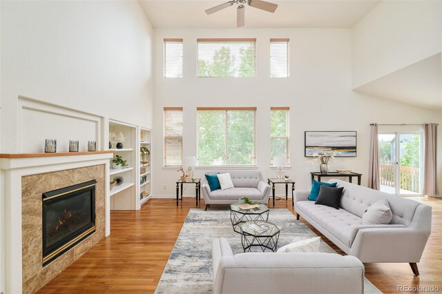 1477 Serene Dr, Erie, CO 80516 - living room with a towering ceiling, light wood-type flooring, a ceiling fan, a tiled fireplace, and baseboards
