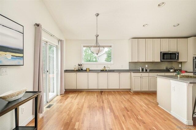 1477 Serene Dr, Erie, CO 80516 - kitchen with stainless steel microwave, light wood-type flooring, black electric stovetop, backsplash, and recessed lighting