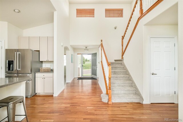 1477 Serene Dr, Erie, CO 80516 - foyer with stairs, light wood-type flooring, high vaulted ceiling, baseboards, and arched walkways