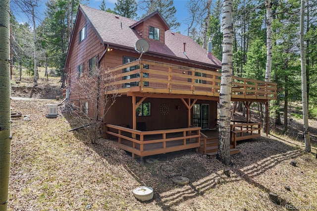 back of house with a wooden deck and roof with shingles