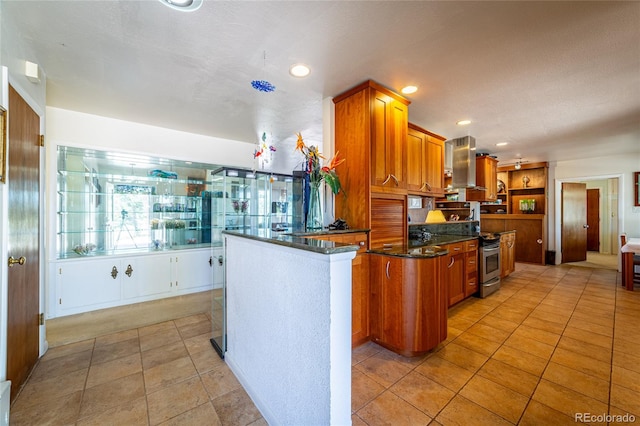 kitchen with kitchen peninsula, light tile patterned floors, range hood, and dark stone countertops