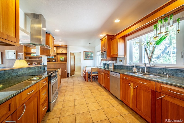 kitchen with hanging light fixtures, sink, light tile patterned floors, wall chimney range hood, and appliances with stainless steel finishes